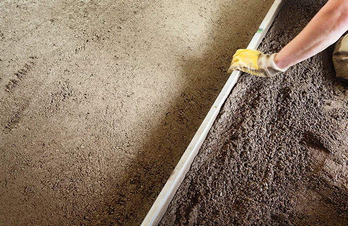 Person verteilt Schüttung mit Richtlatte